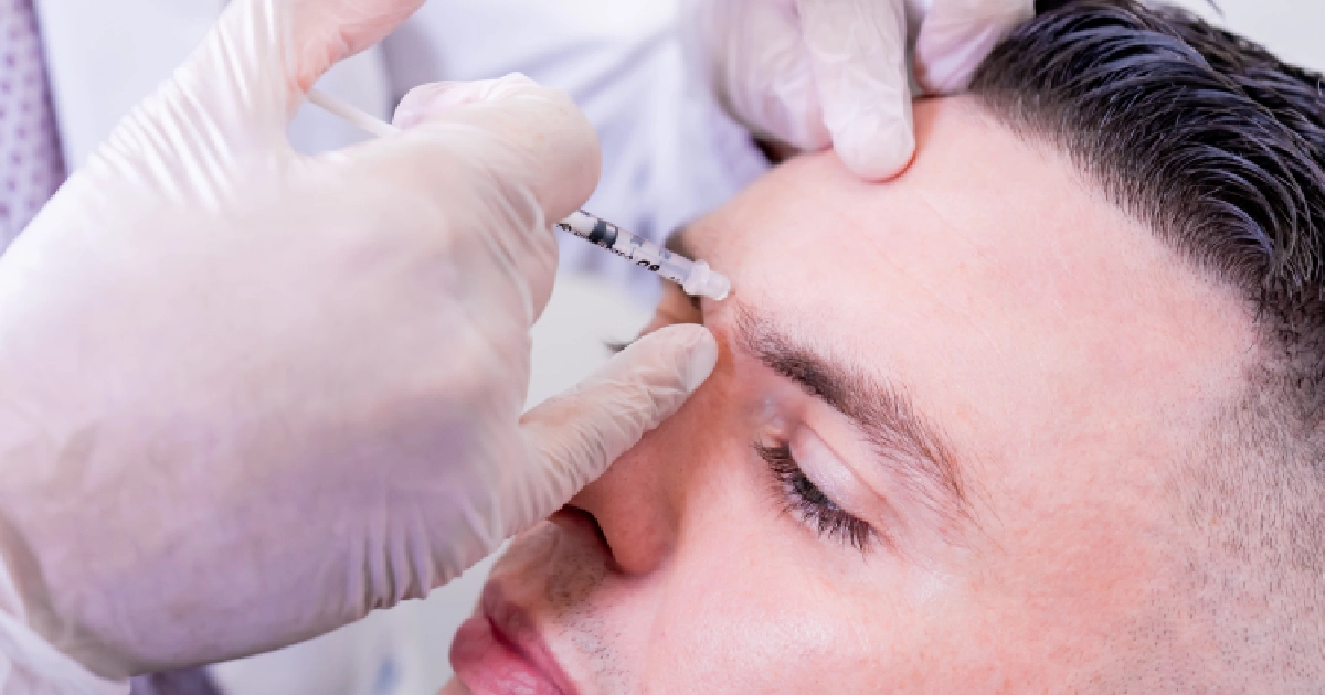 A man receiving a forehead neurotoxin injection in Ellicott City, Maryland from a medical professional wearing gloves.
